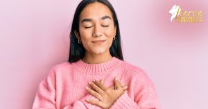 Woman with hands on heart in pink sweater