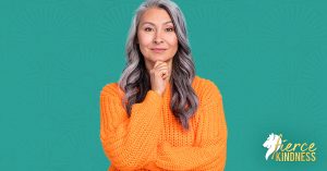 For Resilience: Confident Woman in orange sweater holding chin looking directly at camera