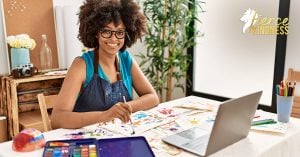 Happy Smiling adult sitting at desk with paints and laptop