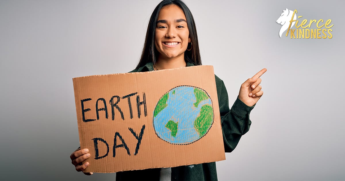 Woman holding Earth Day Sign pointing upwards