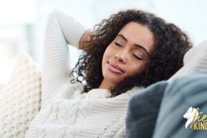 Woman resting, smiling with eyes closed on sofa