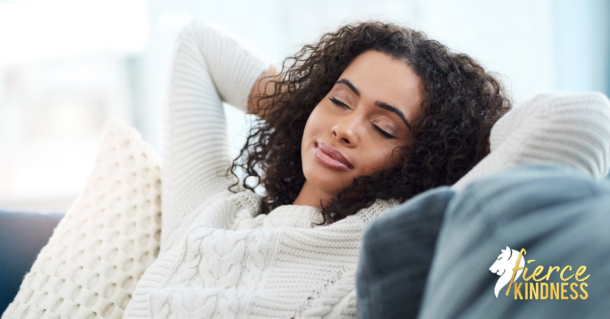 Woman resting, smiling with eyes closed on sofa