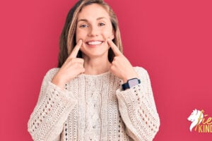 Woman forcing a smile with fingers to show being nice and am I a people pleaser on deep pink background