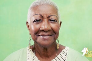Older Black woman smiling against green background