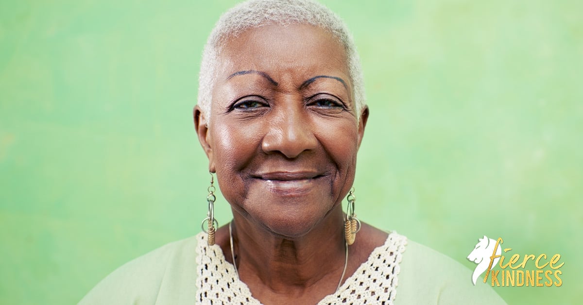 Older Black woman smiling against green background
