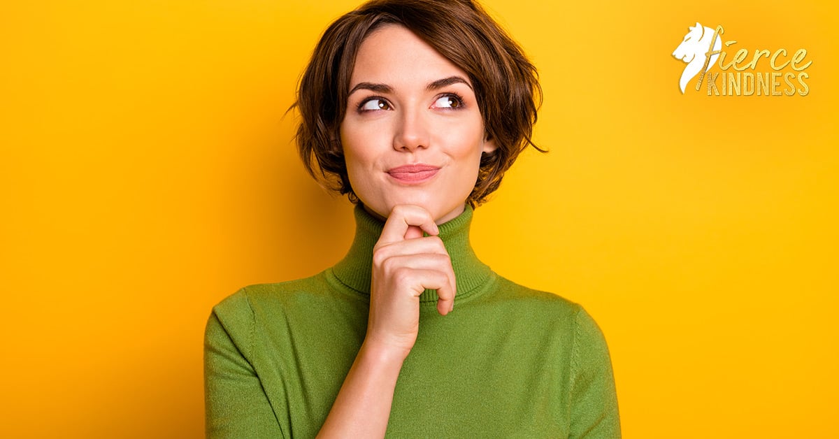 Woman in green sweater pondering, holding chin looking up and right