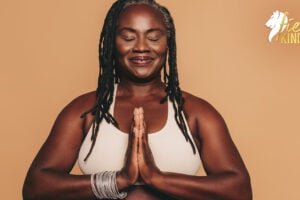 Calm serene woman smiling with hands together against a beige background